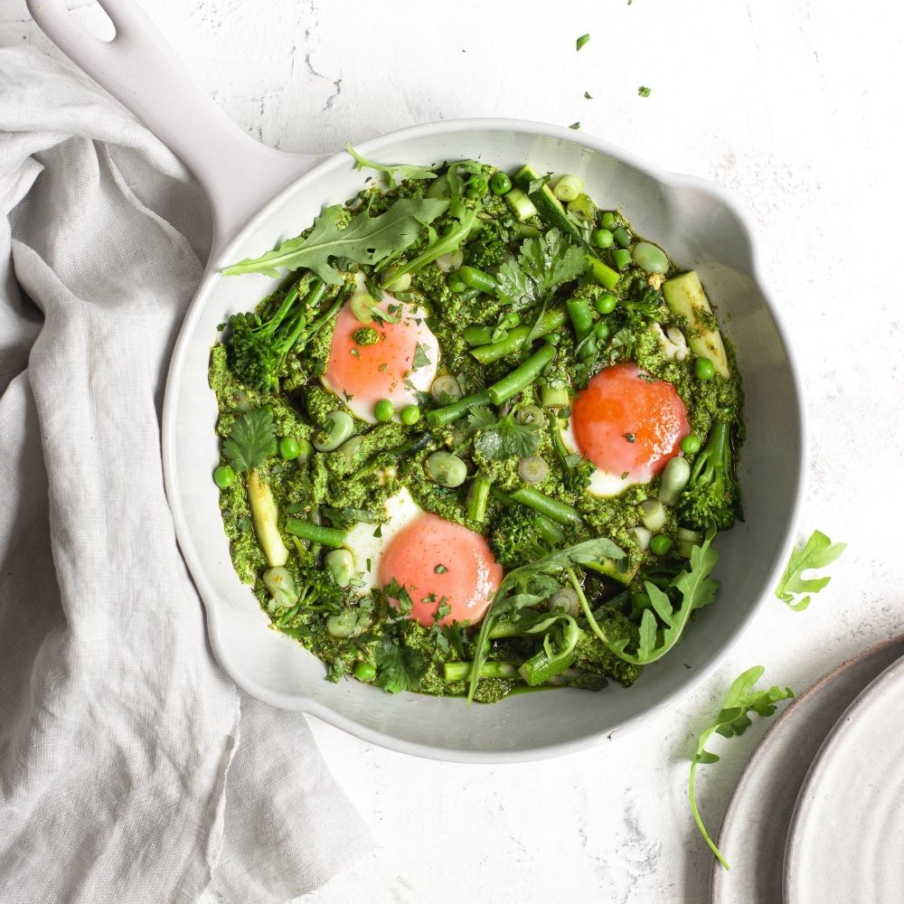 Green shakshuka with eggs in a white skillet, made with spring vegetables and herbs—rich in choline to support brain health and reduce perimenopause brain fog.