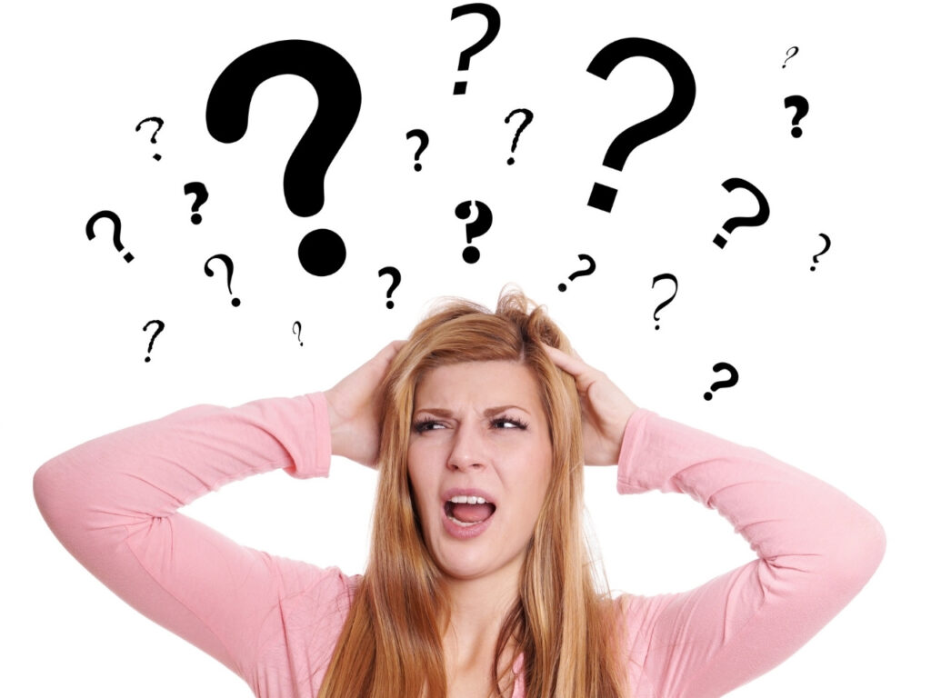 Woman holding head with frustrated expression and question marks overhead, symbolising perimenopause brain fog symptoms like forgetfulness and confusion.