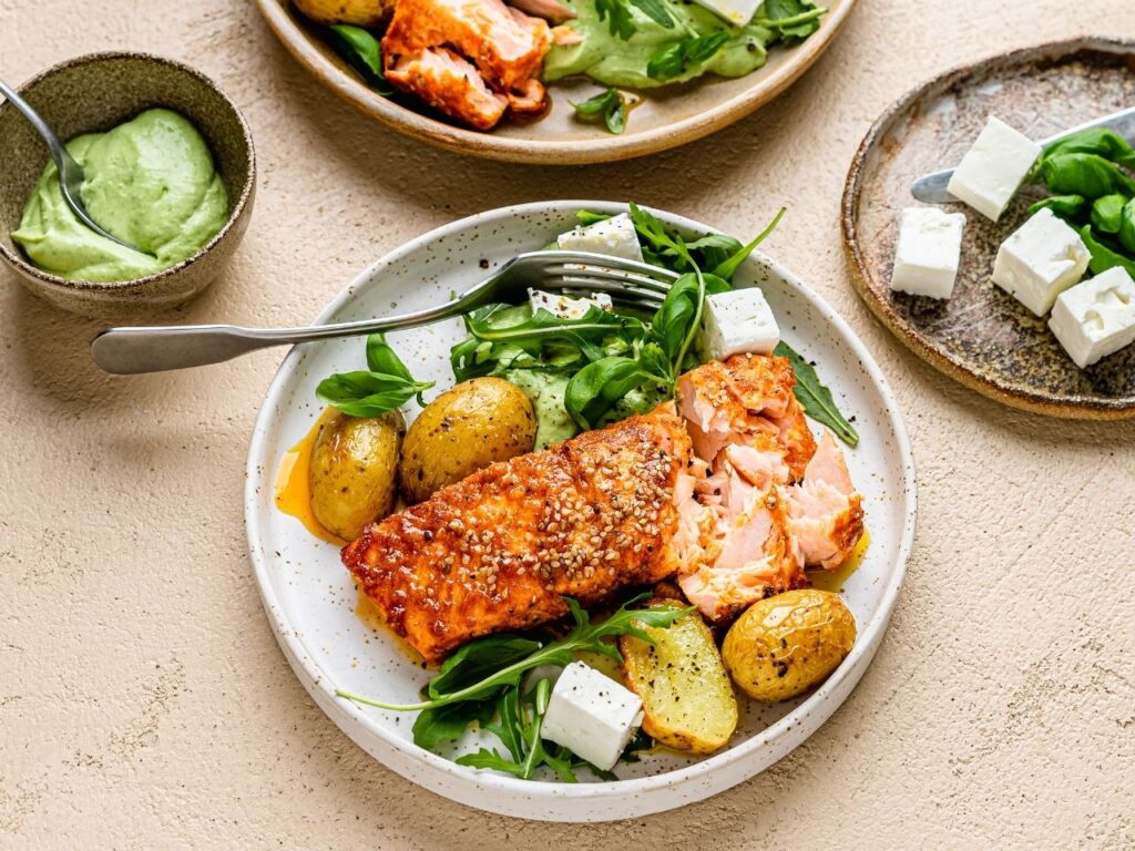 Spiced salmon traybake with baby potatoes, rocket, feta and avocado green goddess dressing – a vitamin D-rich recipe to support brain health in perimenopause.